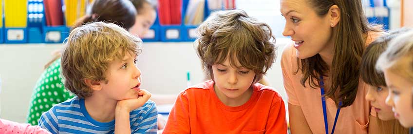 Teacher's Assistant smiling and working with young students