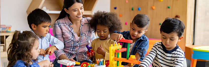 Teacher's Assistant smiling and working with young students