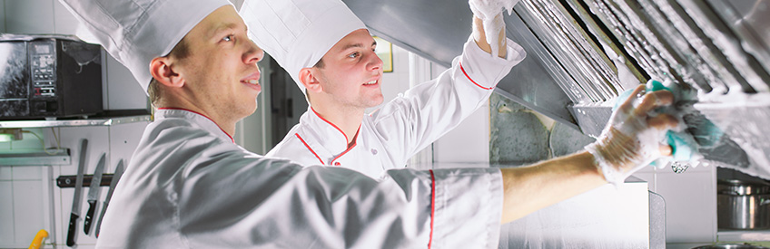 Cooks washing oven, stove and extractor in the Restaurant